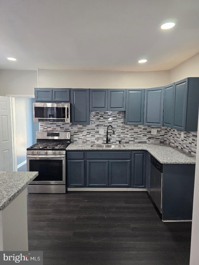 kitchen with recessed lighting, dark wood-style flooring, a sink, appliances with stainless steel finishes, and backsplash