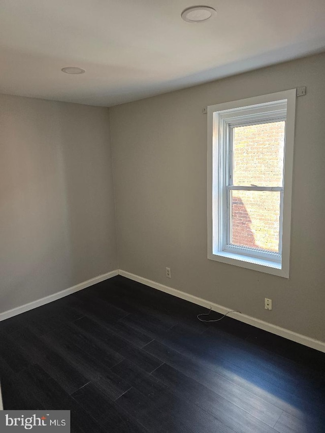 empty room featuring dark wood-type flooring and baseboards