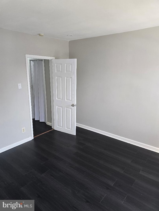 empty room with baseboards and dark wood-style flooring