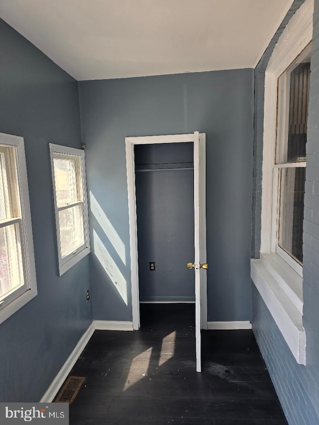 unfurnished bedroom featuring visible vents, baseboards, and wood finished floors