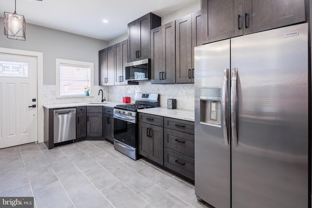 kitchen featuring a sink, backsplash, appliances with stainless steel finishes, and hanging light fixtures