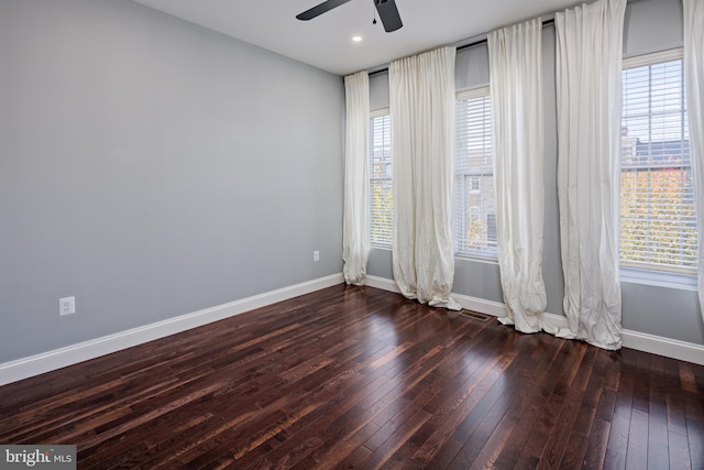 spare room with dark wood finished floors, visible vents, baseboards, and ceiling fan