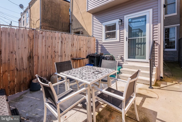 view of patio featuring entry steps, outdoor dining space, and fence