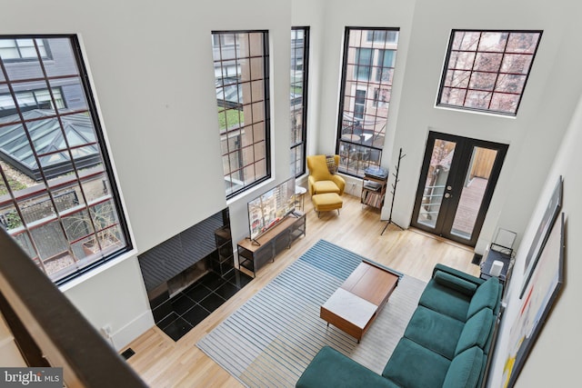 living area featuring french doors, baseboards, a high ceiling, and wood finished floors