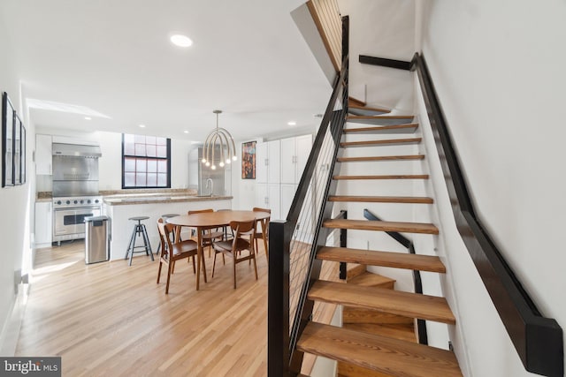 staircase with a notable chandelier, recessed lighting, and wood finished floors