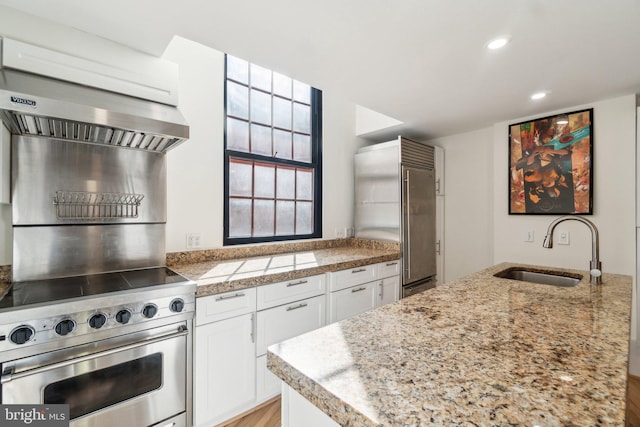 kitchen featuring high quality appliances, a sink, white cabinetry, recessed lighting, and tile counters