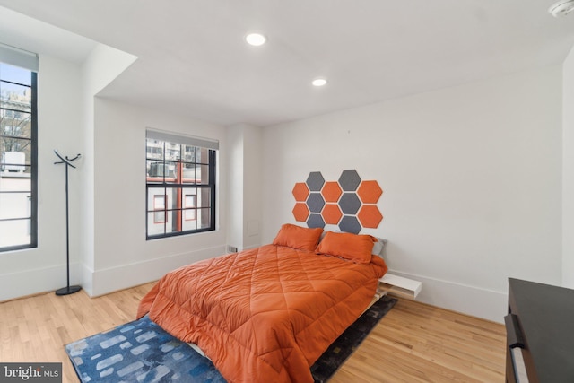 bedroom featuring multiple windows, wood finished floors, and baseboards