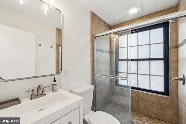 full bathroom with toilet, plenty of natural light, vanity, and a tile shower