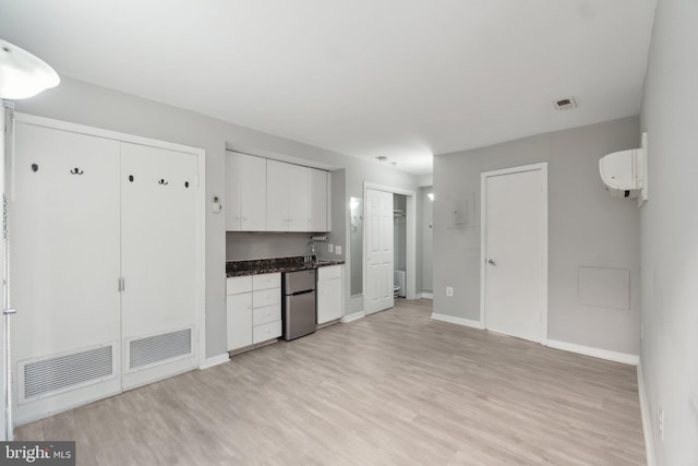 kitchen featuring white cabinetry, refrigerator, visible vents, and light wood-type flooring