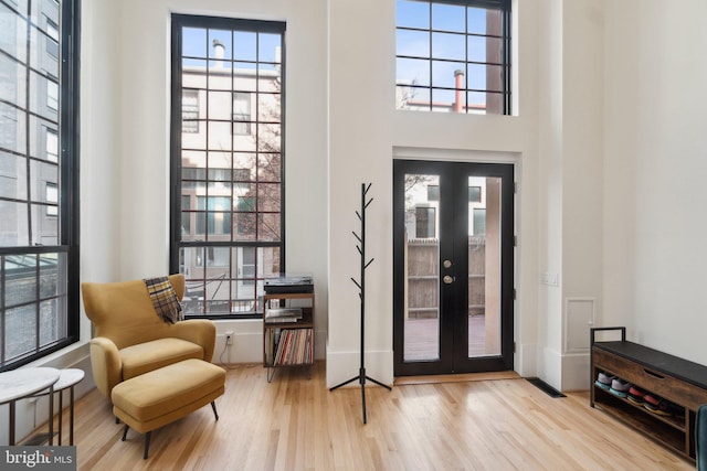 foyer entrance with a towering ceiling, wood finished floors, baseboards, and french doors