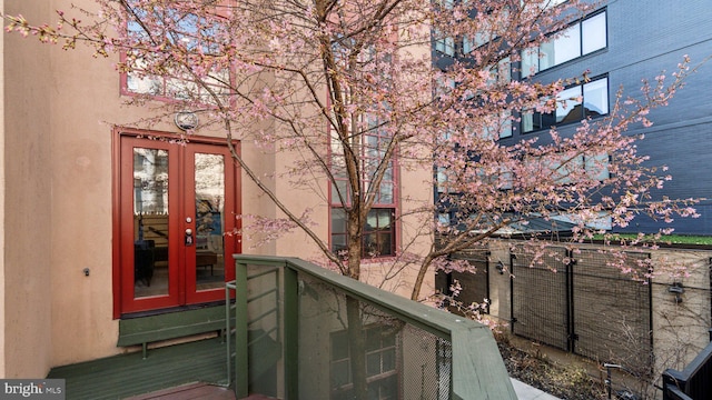 entrance to property featuring a balcony, french doors, and stucco siding