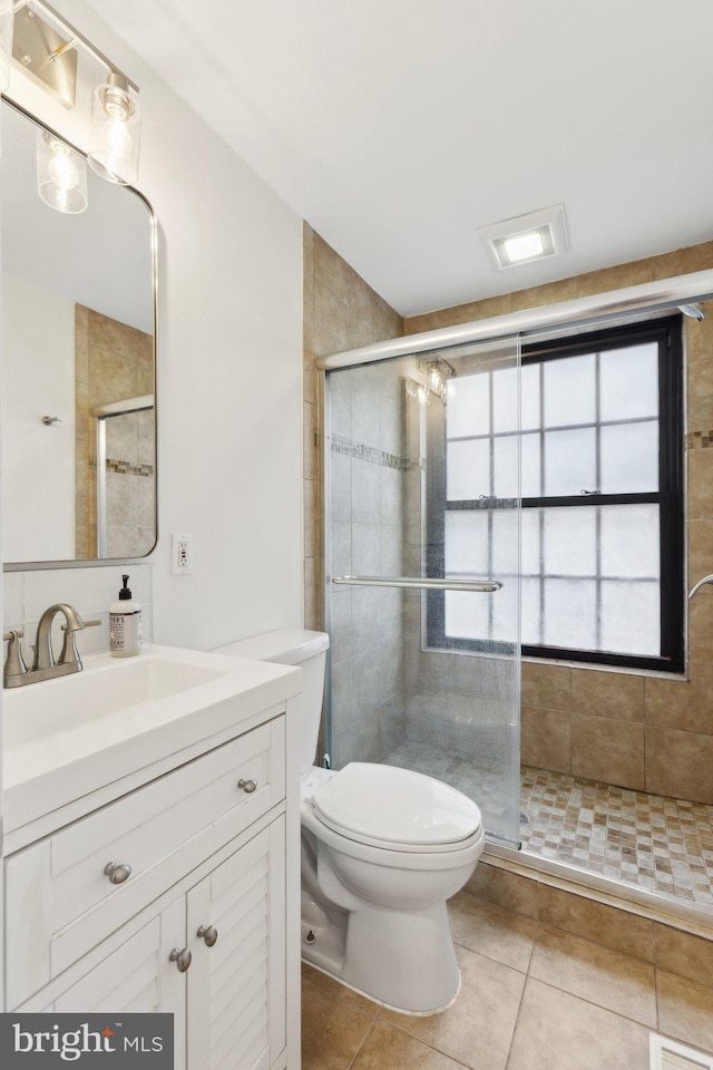 bathroom featuring tile patterned floors, toilet, a stall shower, and vanity