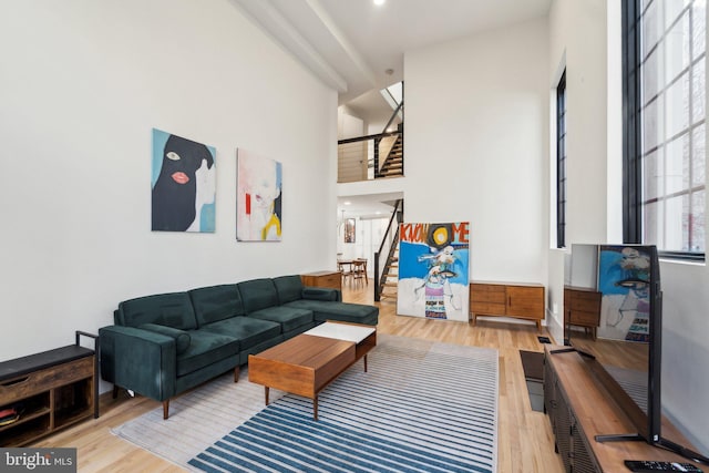 living area with stairway, a towering ceiling, and wood finished floors