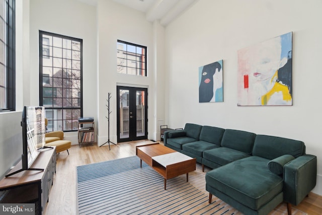 living room with a high ceiling, wood finished floors, baseboards, and french doors