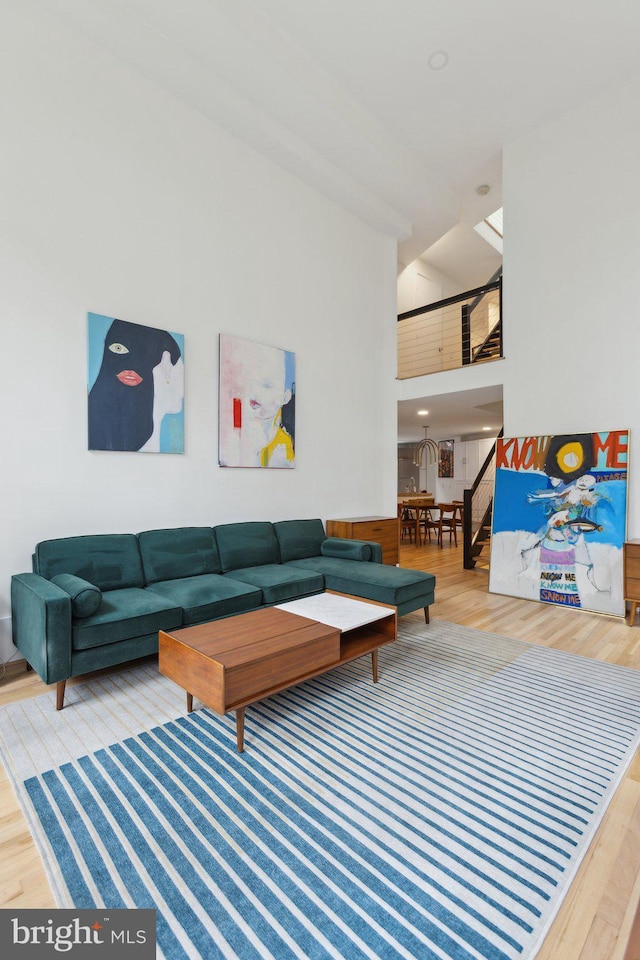 living area with high vaulted ceiling, wood finished floors, and stairs