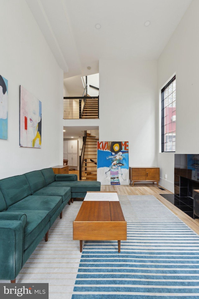 living area with stairway, wood finished floors, and a towering ceiling