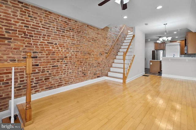 132 N Glover St N, Baltimore, MD 21224 - unfurnished living room featuring a ceiling fan, brick wall, stairs, and light wood-style flooring