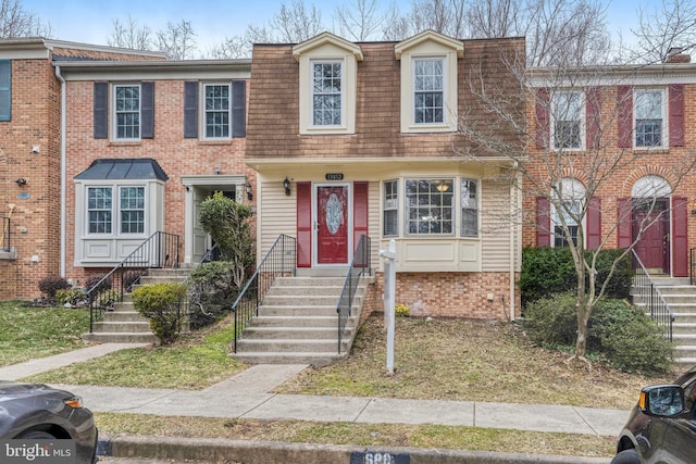 townhome / multi-family property featuring brick siding and mansard roof