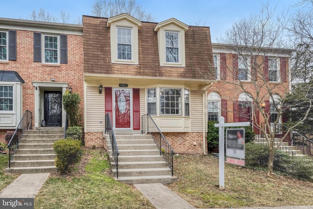 view of property with mansard roof and brick siding