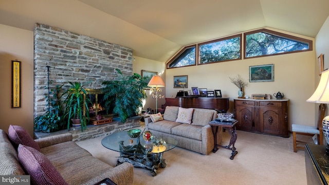 living area featuring a stone fireplace, lofted ceiling, and carpet flooring