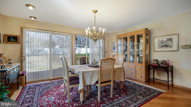 dining area featuring baseboards, an inviting chandelier, and hardwood / wood-style flooring