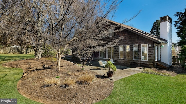 back of house with a patio area, a lawn, a chimney, and fence