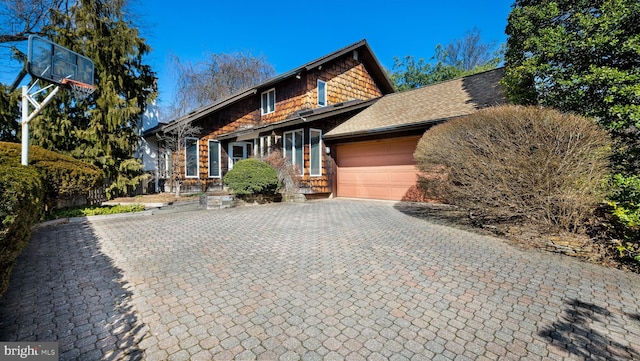 view of front of property with decorative driveway, fence, an attached garage, and a shingled roof