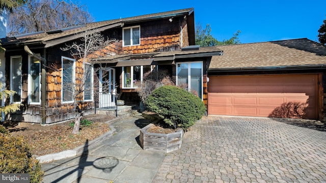 view of front of house with an attached garage, decorative driveway, and roof with shingles