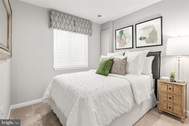 bedroom featuring baseboards, light carpet, and visible vents