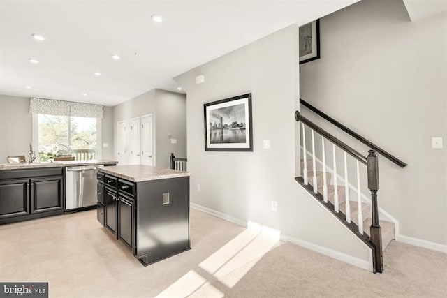 kitchen featuring a sink, a kitchen island, baseboards, dishwasher, and dark cabinets