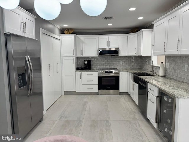 kitchen with light stone countertops, visible vents, a sink, stainless steel appliances, and wine cooler