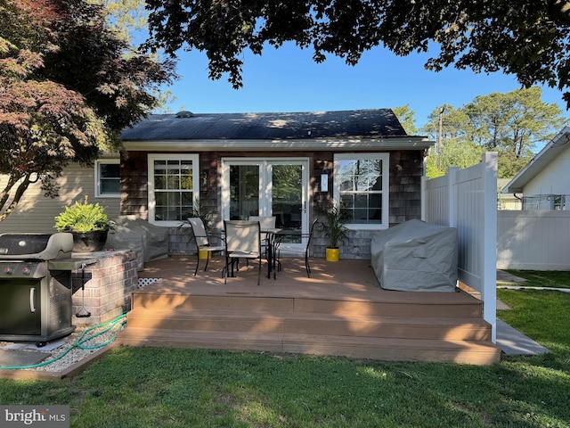 back of property with outdoor dining space, fence, french doors, and a wooden deck