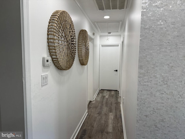 hall featuring visible vents, ornamental molding, baseboards, attic access, and dark wood-style flooring