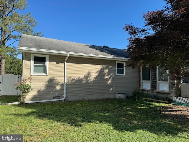 view of home's exterior featuring fence, a yard, and roof with shingles