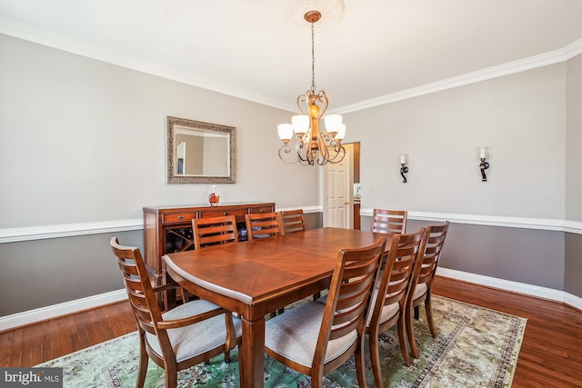 dining area with crown molding, a notable chandelier, wood finished floors, and baseboards