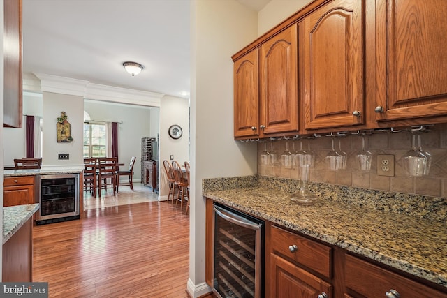 kitchen with wine cooler, backsplash, stone countertops, and crown molding