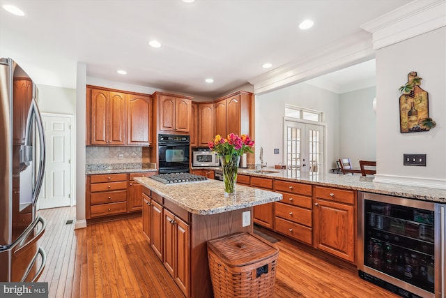 kitchen featuring wine cooler, stainless steel appliances, brown cabinetry, and a sink