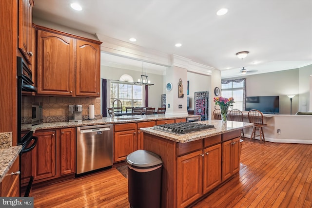 kitchen featuring backsplash, crown molding, light wood-style flooring, stainless steel appliances, and a sink