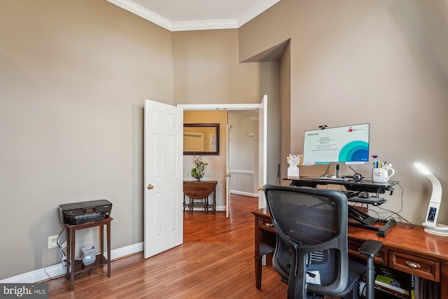 home office with a towering ceiling, crown molding, baseboards, and wood finished floors