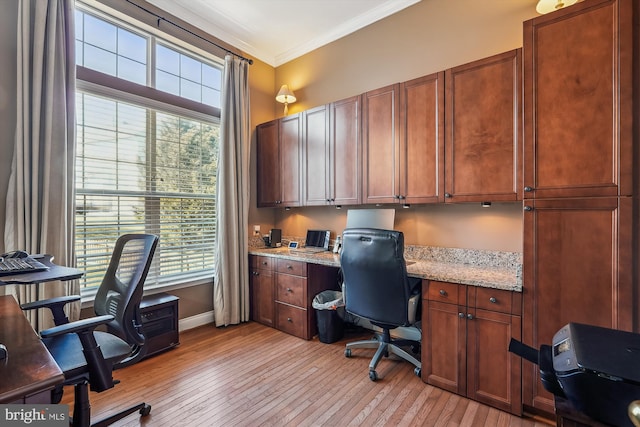 office area with built in study area, baseboards, light wood-type flooring, and ornamental molding