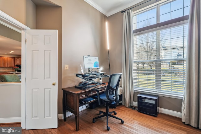 office space with a wealth of natural light, baseboards, wood-type flooring, and crown molding