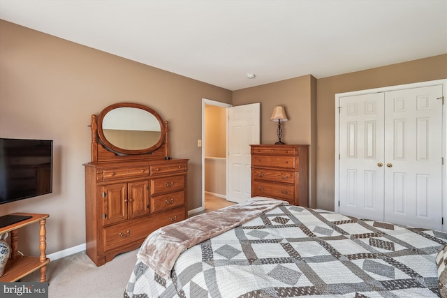 bedroom featuring a closet, light carpet, and baseboards