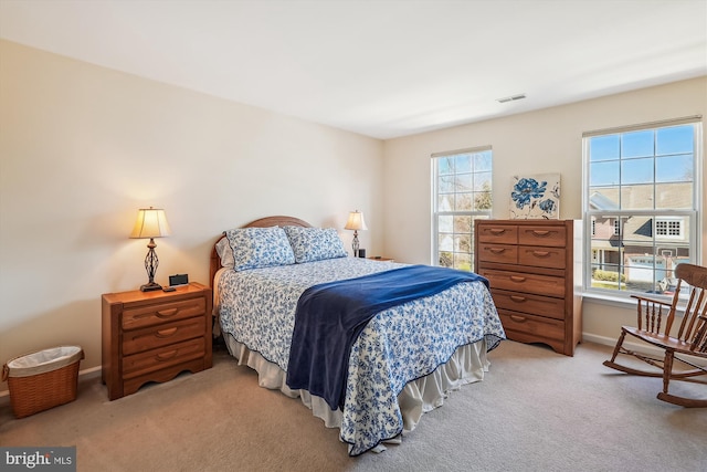 bedroom with visible vents, multiple windows, light colored carpet, and baseboards