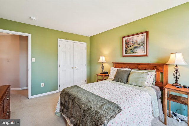 bedroom with a closet, light colored carpet, and baseboards