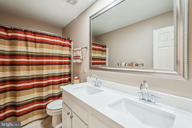 bathroom featuring double vanity, toilet, visible vents, and a sink