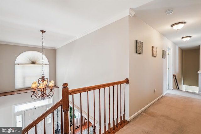 hallway featuring baseboards, ornamental molding, carpet flooring, an upstairs landing, and a chandelier