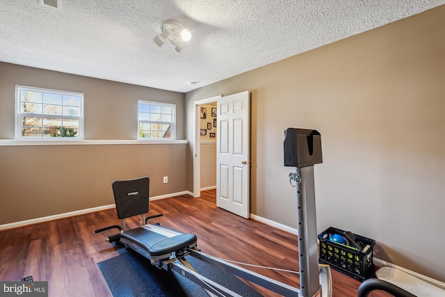 workout room with a textured ceiling, baseboards, and wood finished floors