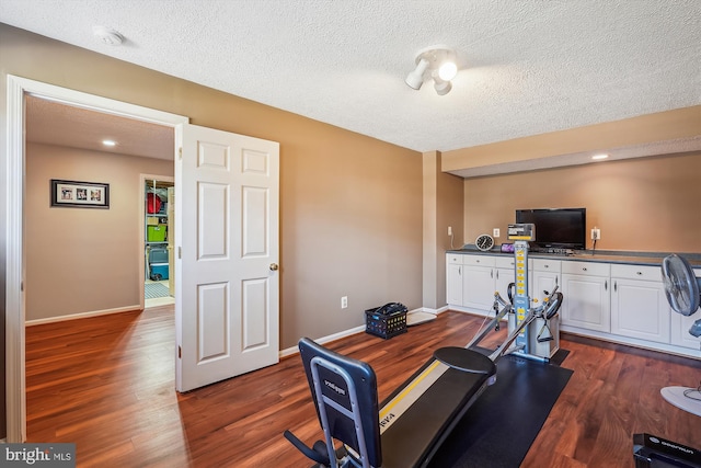 workout room with baseboards, dark wood-style flooring, and a textured ceiling