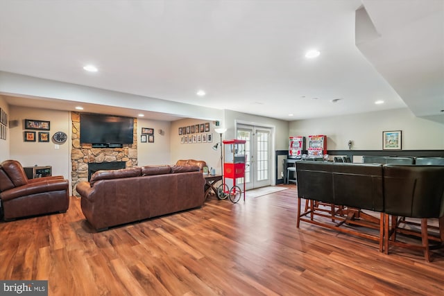 living room featuring recessed lighting, a stone fireplace, and wood finished floors