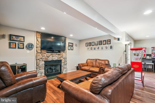 living area with a stone fireplace, recessed lighting, and wood finished floors